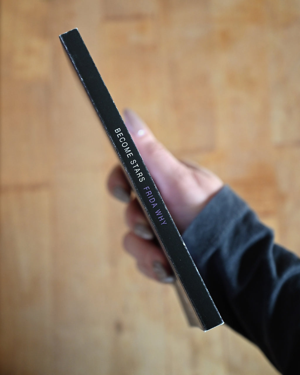 Hand holding a black rectangular object with text on a wooden surface