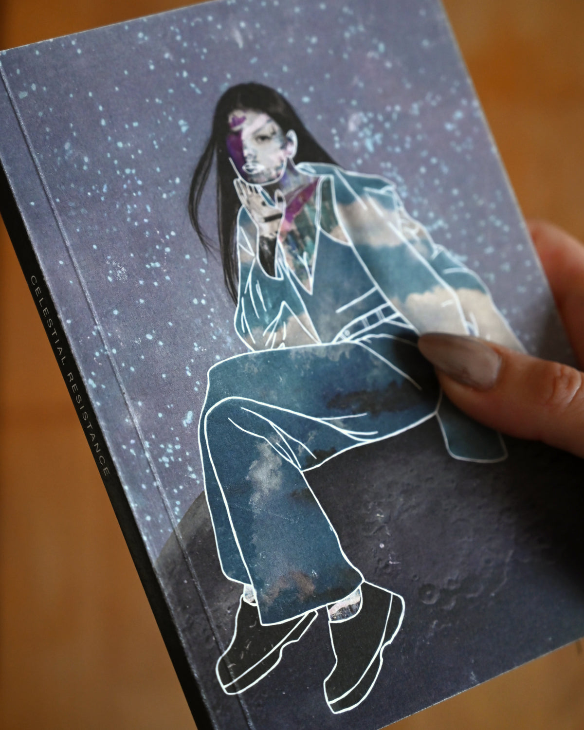 Notebook with an illustration of a person sitting on a cloud against a starry sky.