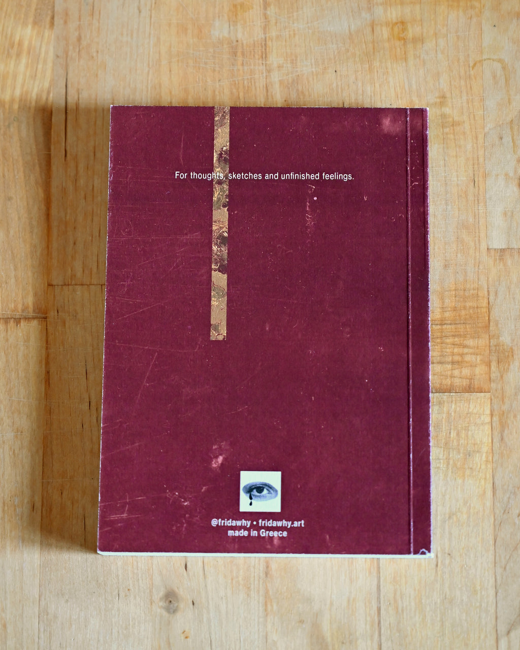 Maroon notebook with text on a wooden surface