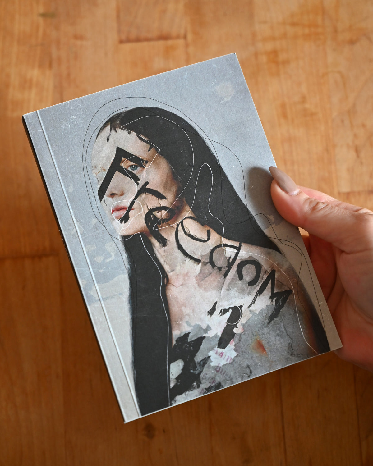 Book with a cover featuring an artistic illustration of a woman's face on a wooden surface