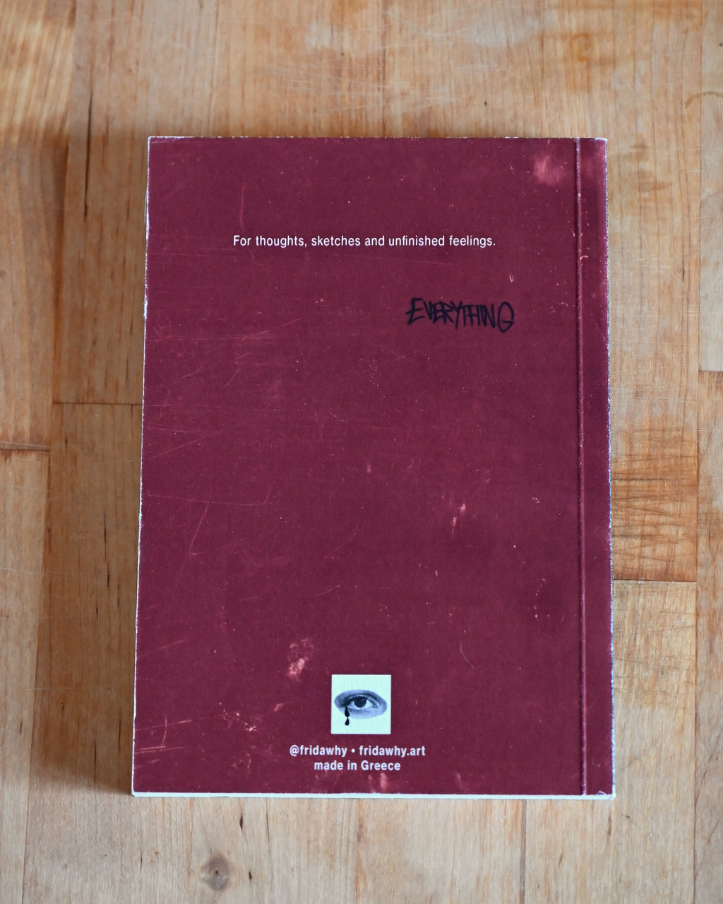 Maroon notebook with text on a wooden surface