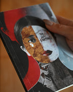Book with a stylized face design held by a hand on a blurred background
