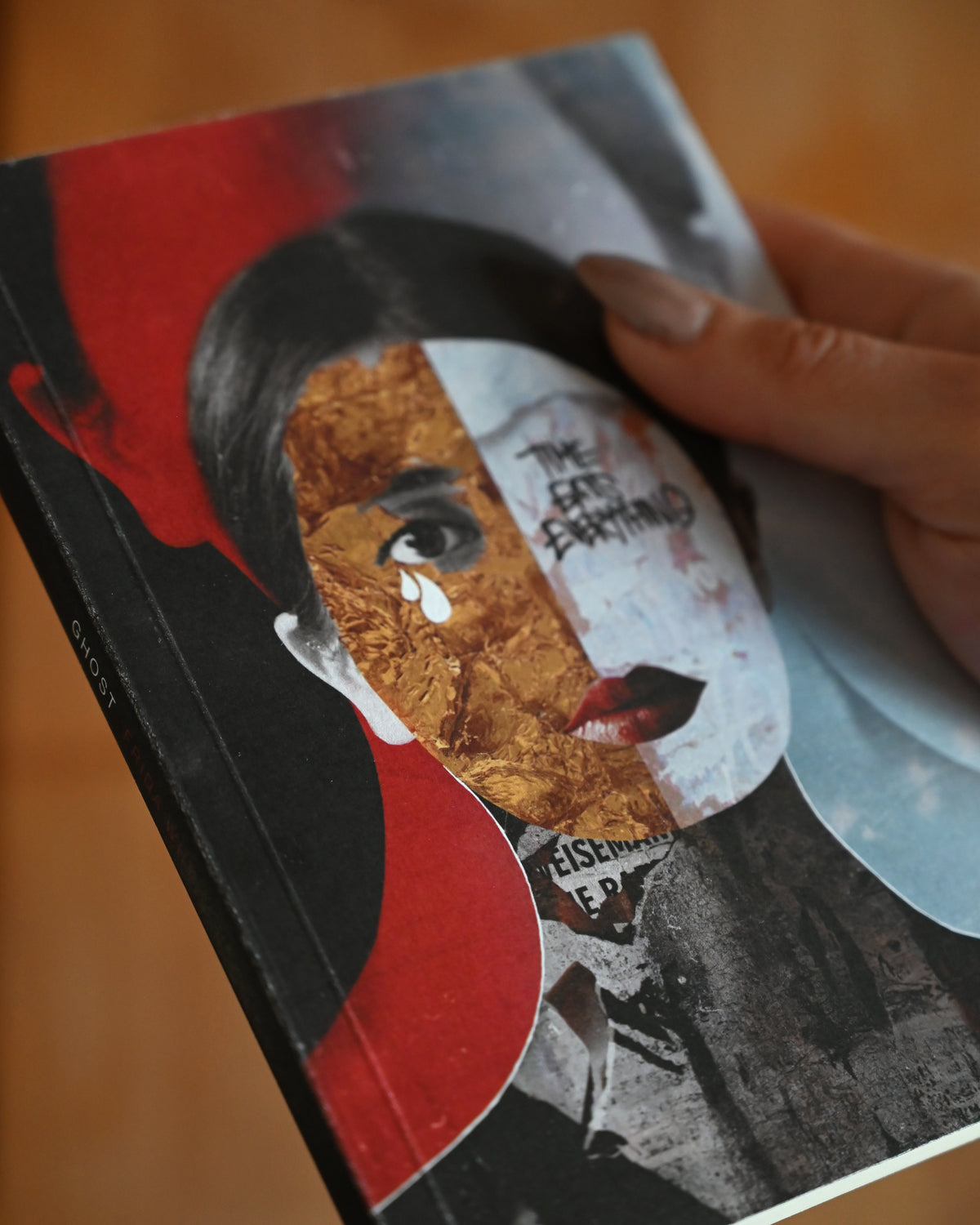Book with a stylized face design held by a hand on a blurred background