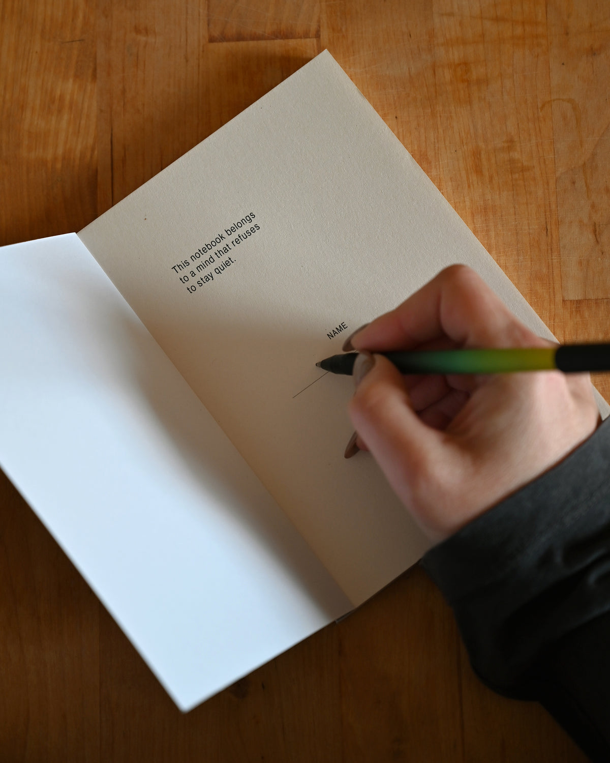 Hand writing in a notebook with a pen on a wooden surface