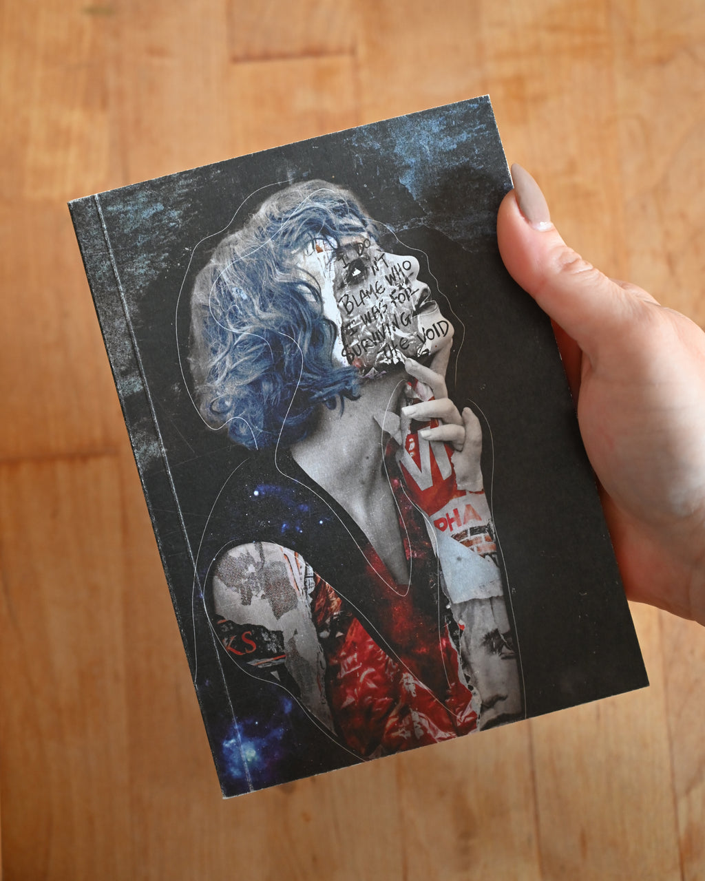 Notebook with a graphic design of a person smoking a cigarette held by a hand on a wooden surface