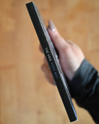 Hand holding a black rectangular object with text on a wooden surface