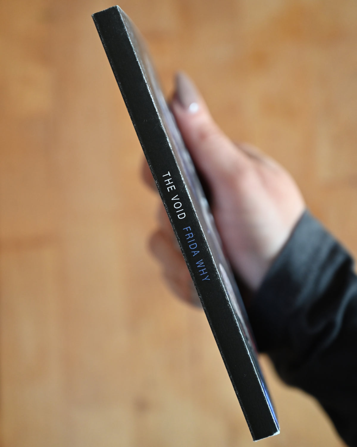 Hand holding a black rectangular object with text on a wooden surface