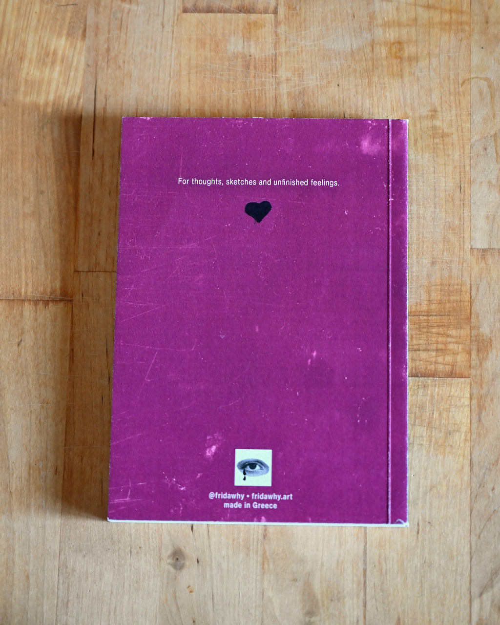 Purple notebook with text and a heart symbol on a wooden surface