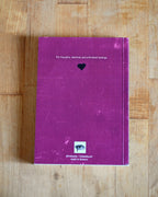 Purple notebook with text and a heart symbol on a wooden surface