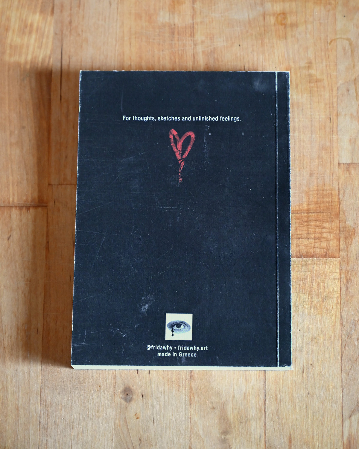 Black notebook with a red heart on a wooden surface