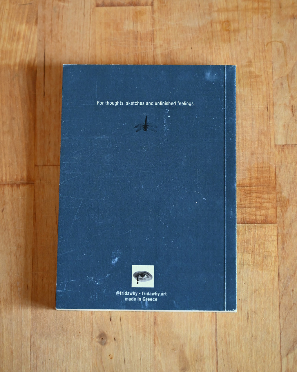 Blue notebook with text and a logo on a wooden surface