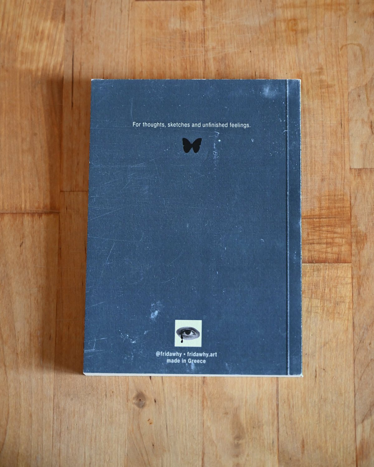 Blue notebook with text and a logo on a wooden surface