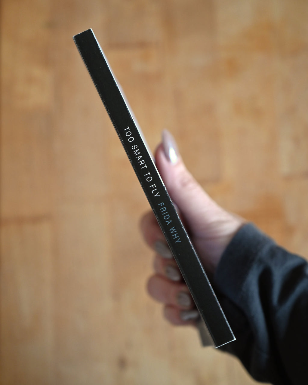 Hand holding a black pen with text on a wooden surface