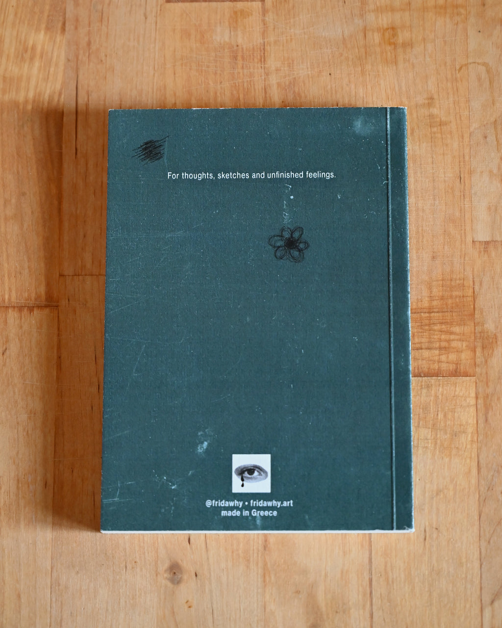 Green notebook with text and minimal design on a wooden surface