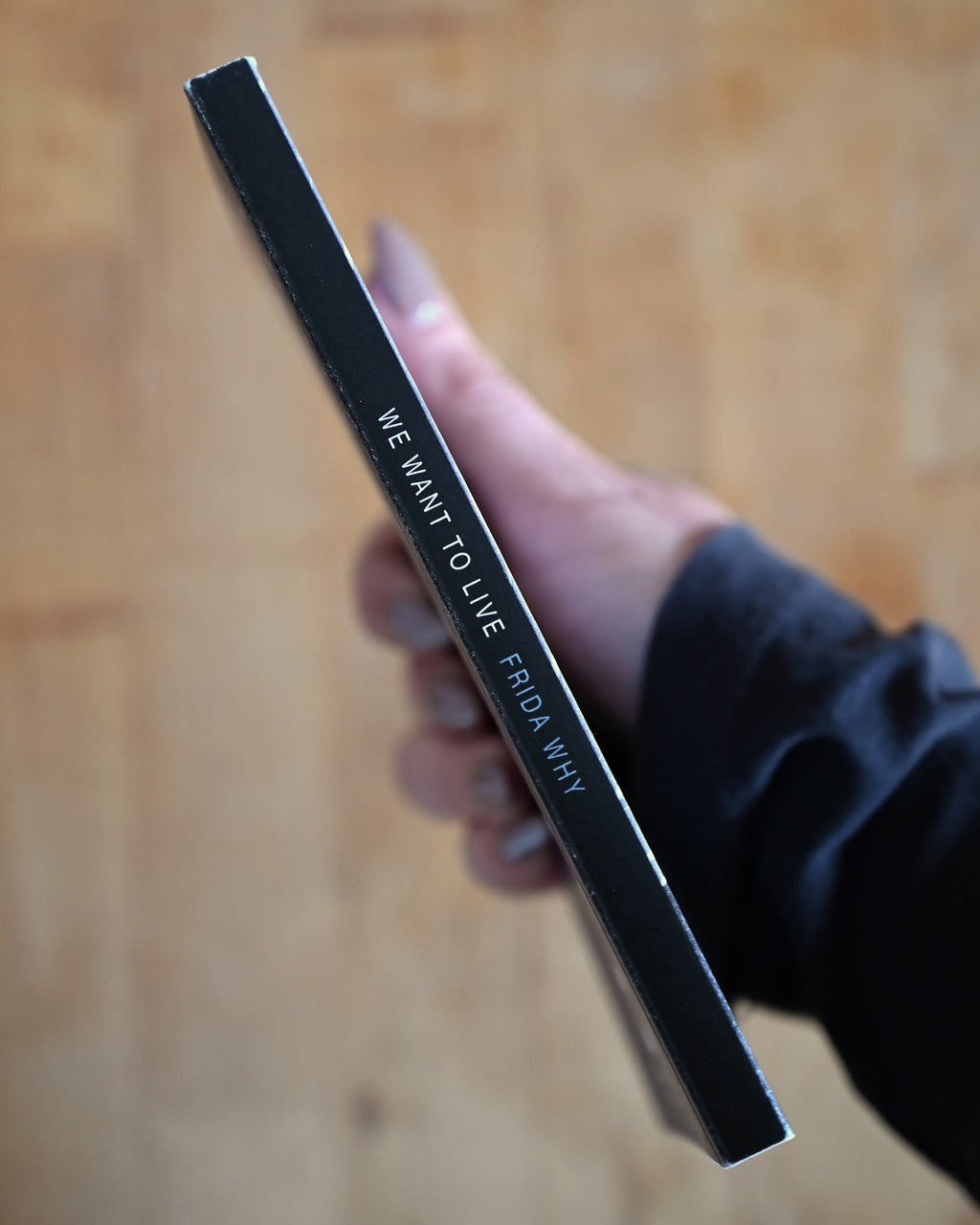 Hand holding a black pen with text on a wooden surface