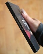 Hand holding a black product box with text on a wooden surface
