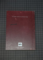 A dark red textured notebook or journal with white text and a small eye logo near the bottom, placed on a dark grid-patterned surface.