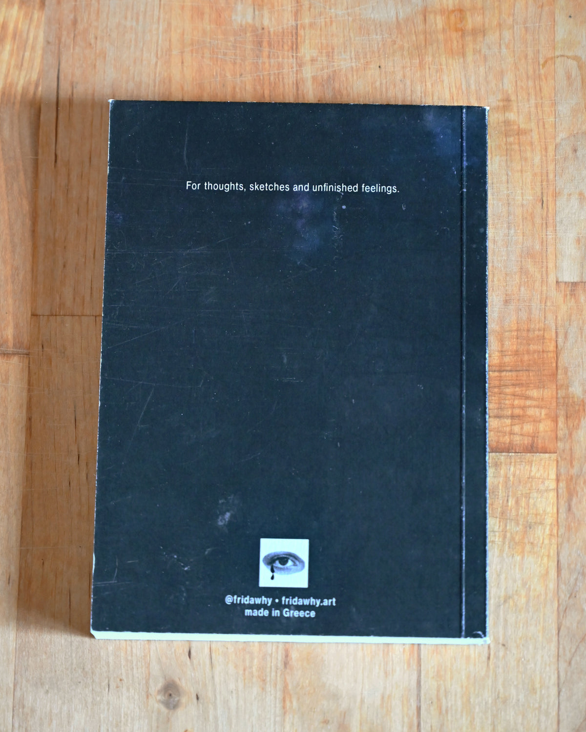 Black notebook with text on a wooden surface