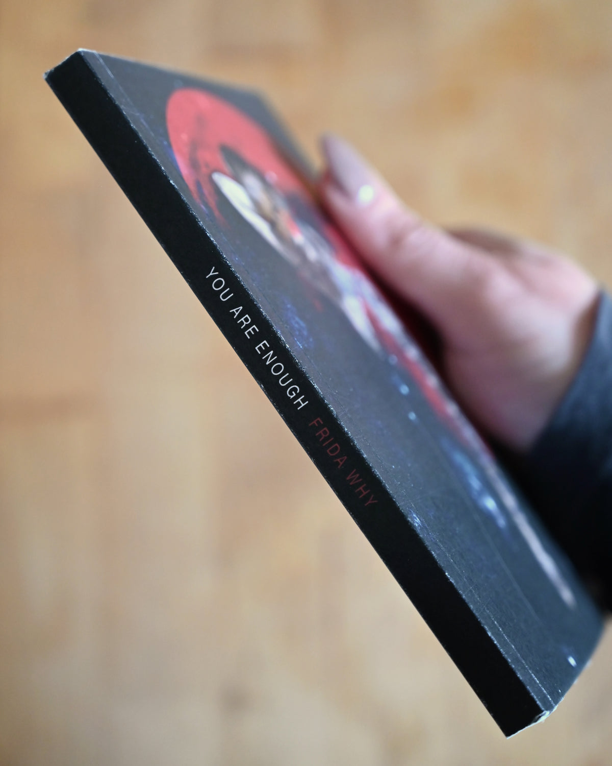 Person holding a book titled 'You Are Enough' with a blurred background
