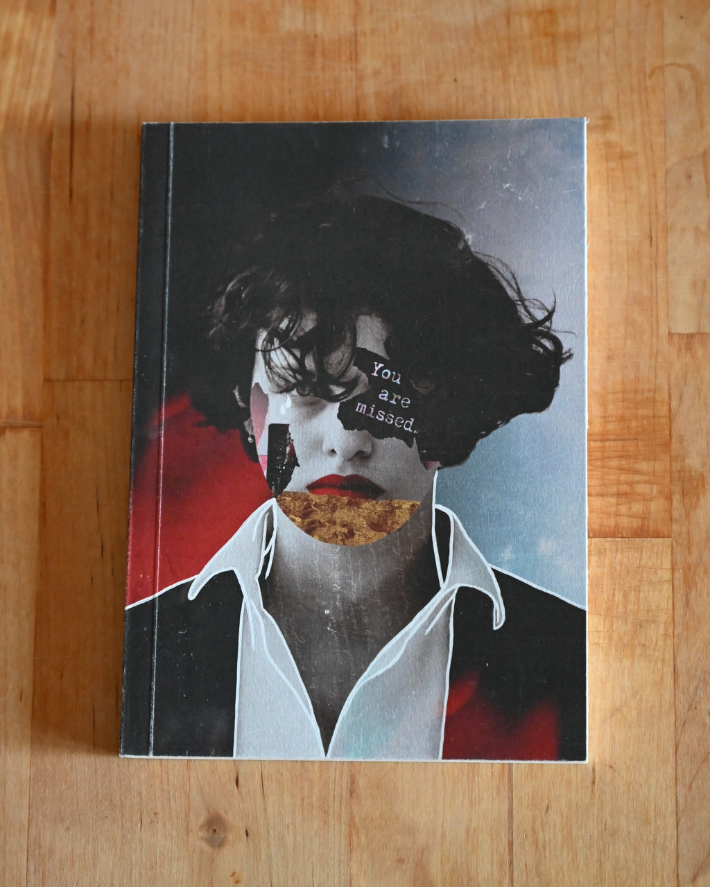 Book with artistic cover featuring a face and text on a wooden surface