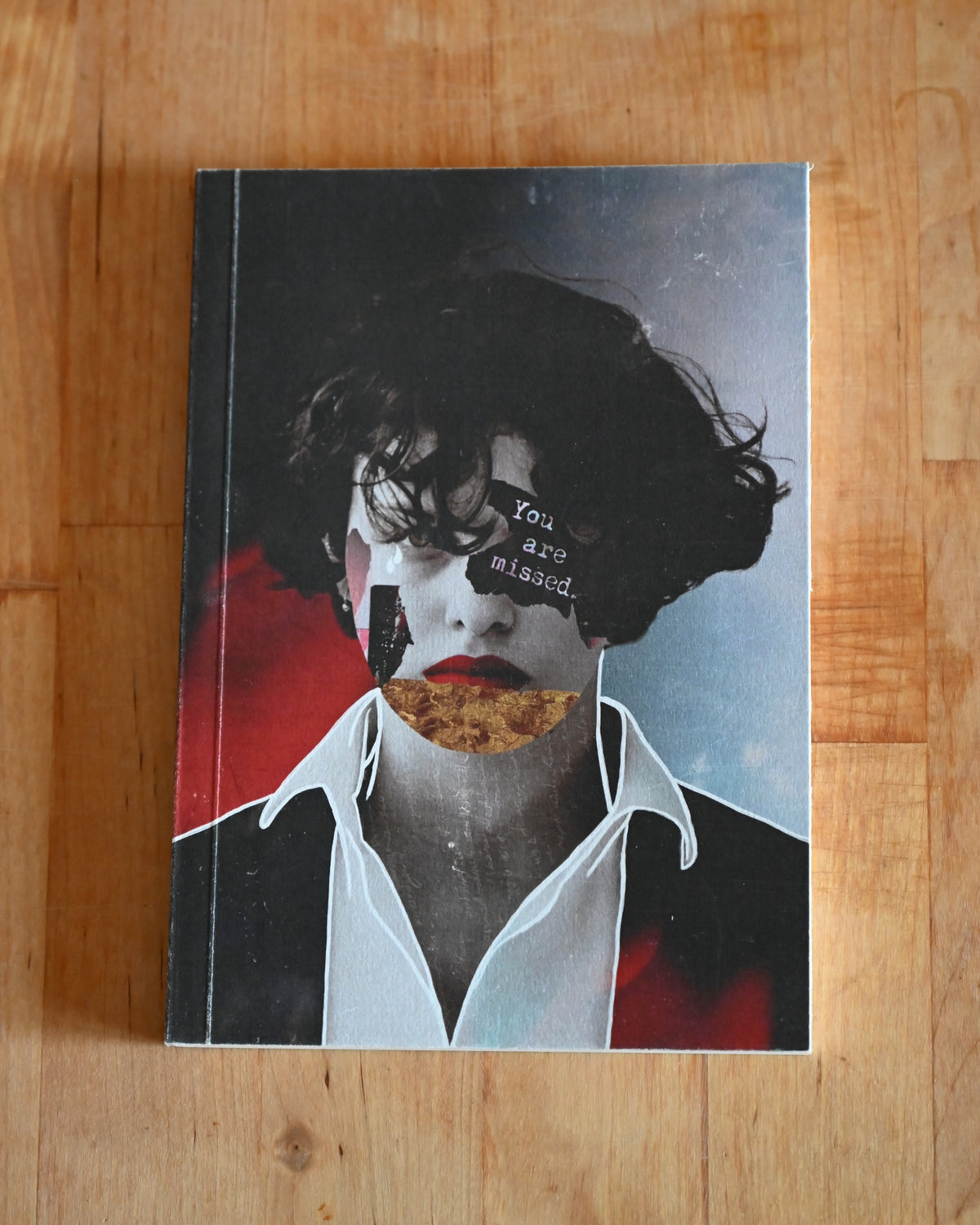 Book with artistic cover featuring a face and text on a wooden surface
