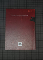 A textured red sketchbook or notebook with white text reading 'For thoughts, sketches and unfinished feelings.' lies on a dark grid-patterned surface.