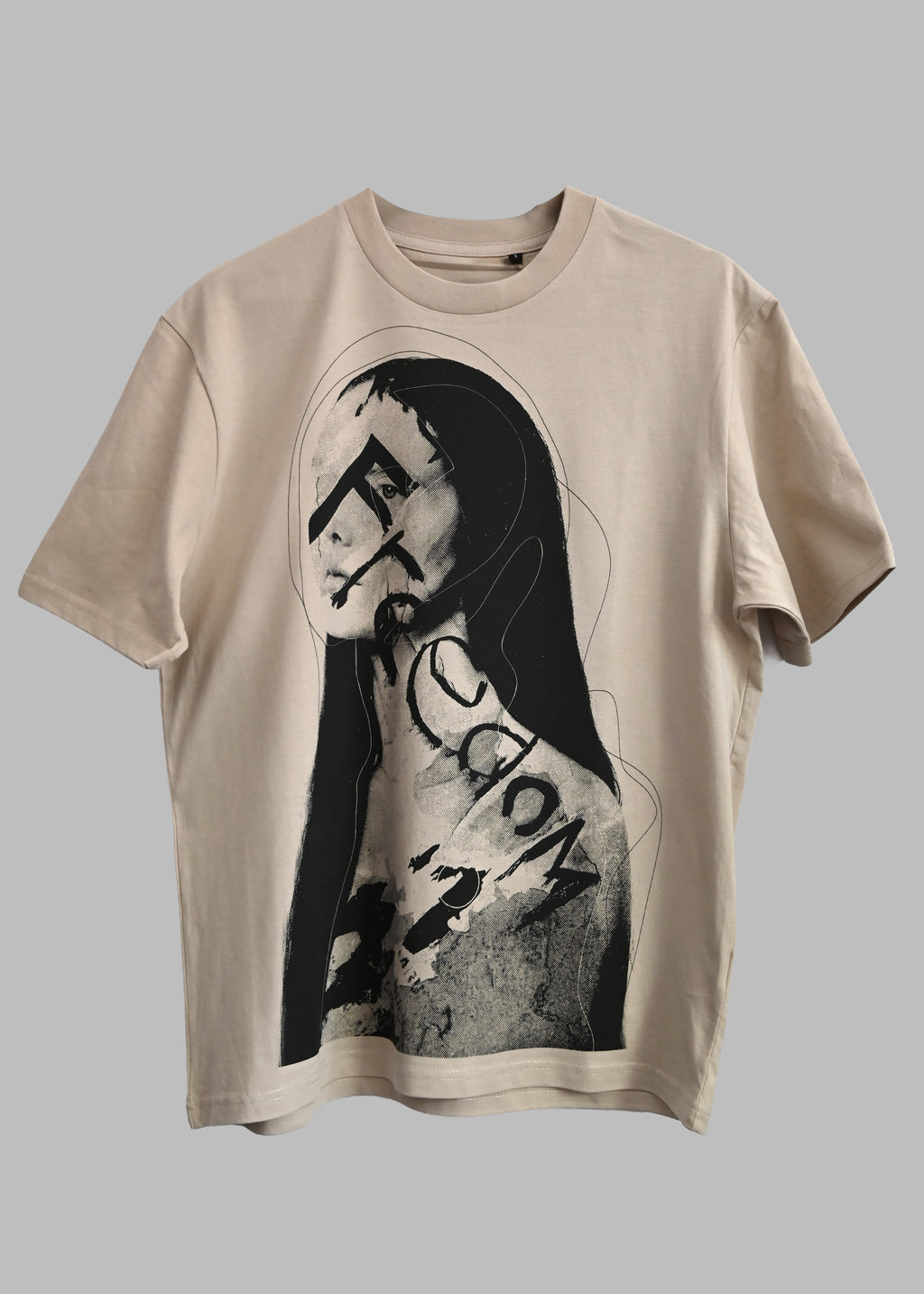 A beige short-sleeve t-shirt featuring a black and white graphic print of a stylized Mona Lisa face with the word 'Fiction' written across her chest, displayed against a solid gray background.