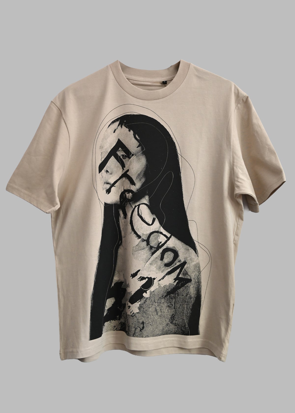 A beige short-sleeve t-shirt featuring a black and white graphic print of a stylized Mona Lisa face with the word 'Fiction' written across her chest, displayed against a solid gray background.
