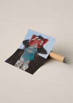 A square art poster with a surreal collage illustration of a figure in black and red against a light blue background, shown leaning against a cardboard mailing tube on a warm beige surface.