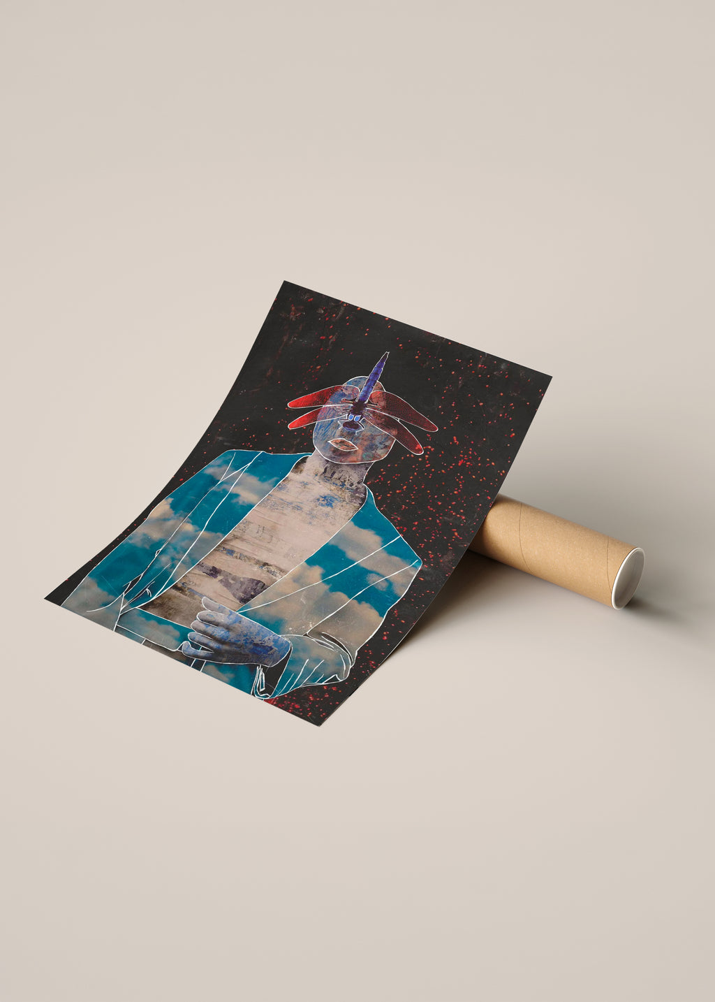 A rolled art print or poster lies on a cardboard tube, partially unrolled to show a surreal collage-style illustration with a blue-clad figure, red accents, a dragonfly and a dark background.