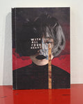 A square art print or book cover standing upright on a red surface against a white wall. The artwork shows a stylized portrait with the text 'WITH ALL YOUR HEART' over a face obscured by dark hair, red abstract background shapes, and a vertical gold-toned textured stripe.